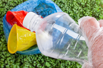 Recycling in Action: A gloved hand holds a plastic bottle among recyclable waste, highlighting environmental responsibility.