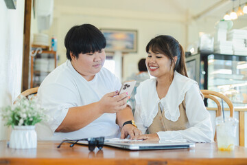 Fototapeta premium Asian couple from lgbtq community enjoy lifestyle activity together looking at smartphone with smiles in cozy cafe setting