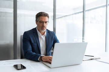 Busy latin male executive businessman looking on computer thinking, working on finance data sitting...