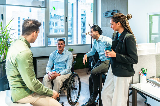 Diverse business team discussing during meeting in modern office with disabled colleague - Powered by Adobe