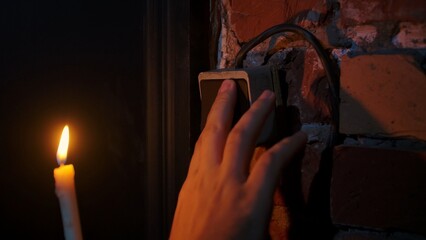 Hand Touching Light Switch Next to Candle Flame
