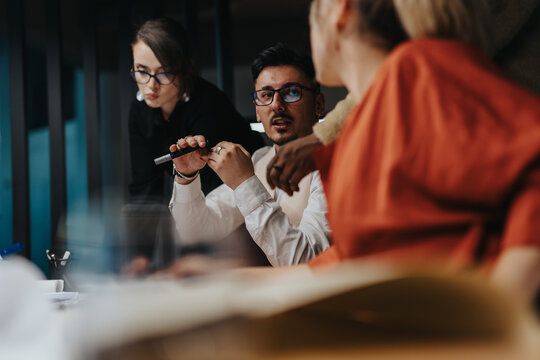 Business people engaged in a lively discussion, showcasing teamwork, creativity, and innovative thinking in a modern office setting. The image highlights a collaborative work environment.