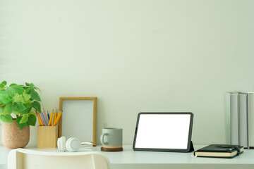 Fototapeta premium Creative workspace with blank tablet screen, framed photo and potted plant, ideal for showcasing productivity, or website mockups.