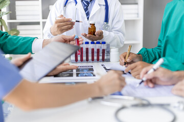 Medical team discussing diagnosis and treatment using x-ray and blood test results. Doctors is analyzing x-ray results and blood test sample to determine the best course of treatment for patient. © Wasan