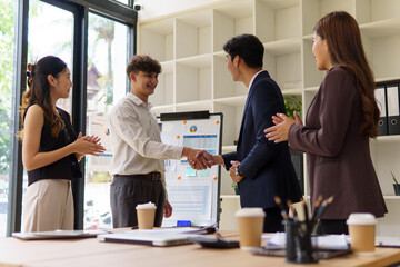 Business partners shaking hands and smiling after closing a successful meeting.