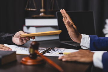Honest officials refuse bribes. Lawyer refusing a bribe from a businessman in his office, he is pushing back the envelope with his hand.
