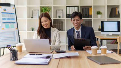 Two business professionals reviewing documents and discussing plans at a meeting.
