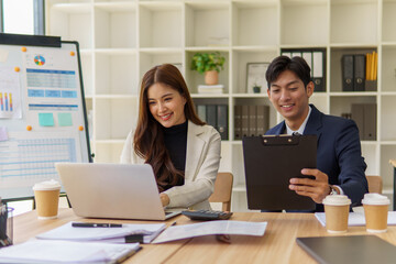 Two colleagues sharing ideas while analyzing reports and working on laptops.