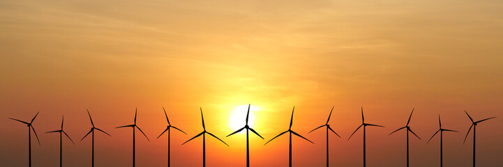 Wind Turbines at Sunset: A stunning silhouette of wind turbines against a vibrant sunset,...