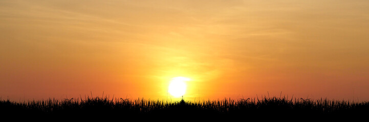 Sunset Silhouette Over Landscape: A serene capture of the sun setting, casting a warm orange glow...