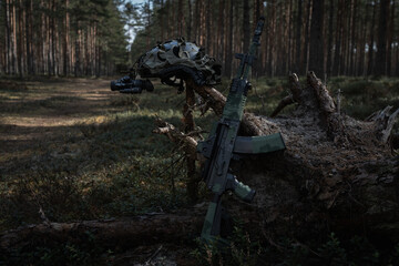 Tactical helmet with night vision device and assault rifle in the forest at sunset, ready for a...
