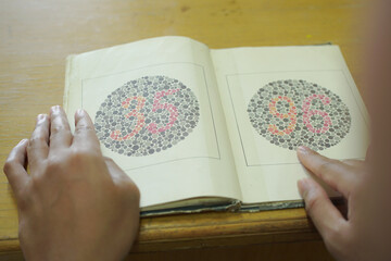 Man get color blindness tested with color blindness cards, vision and eye care concept