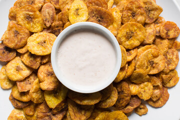 Overhead view of plantain chips on a white countertop, top view of fried ripe plantains on a white background © this_baker