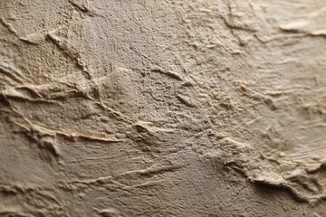Fototapeta premium Close-up beige textured surface, showing uneven, rough strokes creating a three-dimensional effect, suitable as a background for design projects