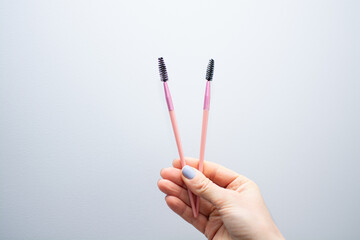 Woman holding pink eyebrow brush close-up. Eyebrow artist paints eyebrows with dye