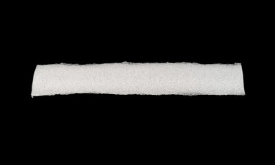 A long, white, textured roll against a black background.
