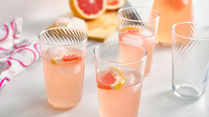 Refreshing grapefruit drinks served in clear glasses with slices of lemon and grapefruit on the table.