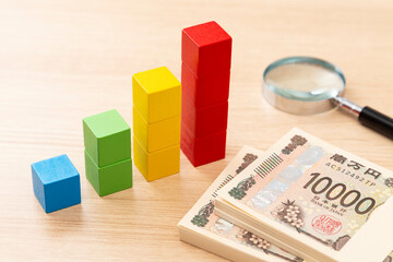 積木で作られたグラフと200万円と虫めがね