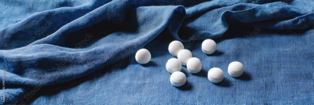 Fototapete soft minimalist still life showcasing white pills arranged on blue fabric in a calm and serene setti