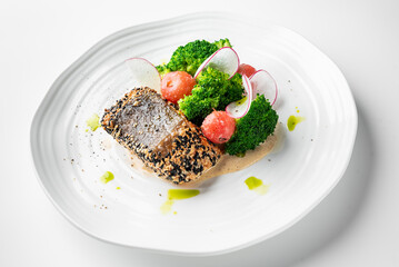 A gourmet dish featuring sesame-crusted fish, elegantly plated with fresh broccoli, radish slices, and melon balls, drizzled with creamy sauce and green oil for a sophisticated culinary presentation.