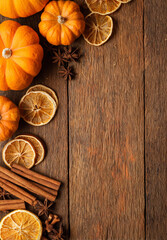 Pumpkin, dried orange, cinnamon, and star anise arranged on rustic wood evoke cozy autumn atmosphere with warm spicy colors and natural textures