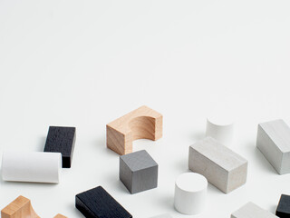 Games with colorful wooden bricks on a white wooden table. The child plays with geometric shapes made of natural wood. Learning and education concept.