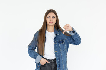 Young sad displeased unhappy woman wear white t-shirt and jeans coat showing thumb down dislike...