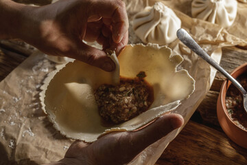 Hands expertly mold khinkali, the traditional Georgian dumplings, in bright sunlight, showcasing fresh ingredients and the art of cooking in action.