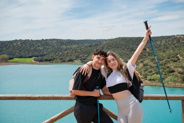 Smiling young couple hugging and celebrating during hike by mountain lake