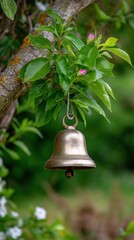 Brass bell hangs from a branch of blossoming pink flowering tree in garden setting meditation reminder sound