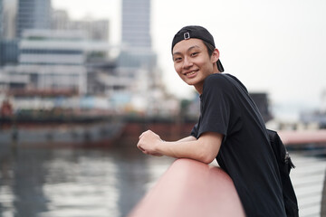 happy young Asian man relaxing at waterfront
