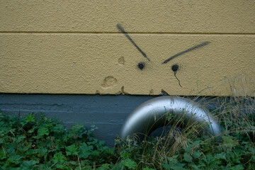 Curved silver colored pipe and lines on the wall makes it look like an angry face