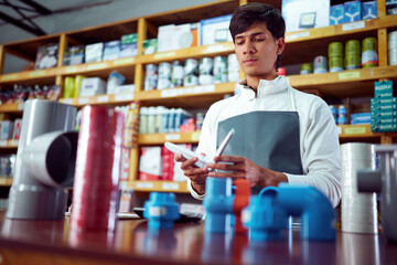 Shop assistant comparing plumbing pipes in hardware store