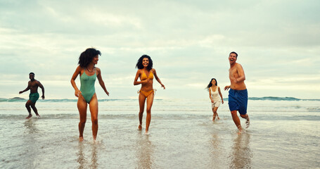 Happy, running and people on beach for travel, freedom and excited on summer vacation. Friends, energy and playing in ocean water for holiday, adventure and bonding at reunion at tropical island