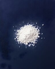 A small mound of fine, white powder sits on a dark blue background