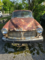 Front View of a Rusty Vintage Car Parked Outdoors