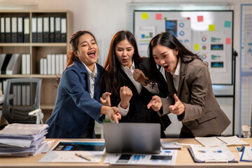Three women are laughing and pointing at a laptop screen