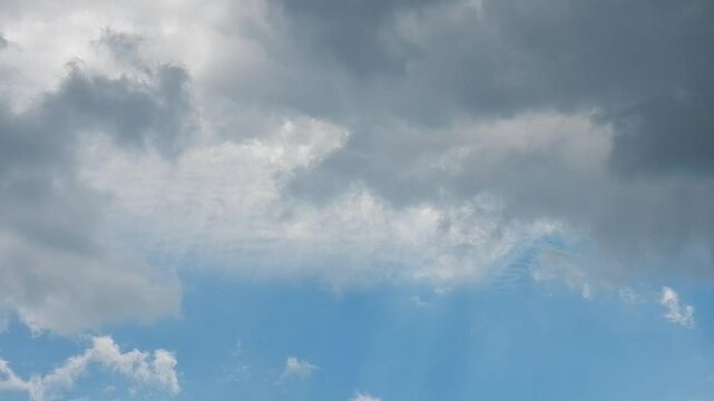 Natural blue and cloudy sky background with moving different types of white Cirrus and rainy grey clouds at different heights. Topics: weather change, climate, cloudscape, meteorology, airspace