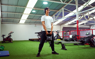 Concentrated sportsman exercising with kettlebell in modern gym