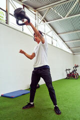Determined athlete lifting kettlebell in modern gym: enhancing strength and fitness