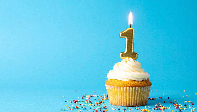 Birthday cupcake with burning number 1 candle, blue background. One year celebration. Tasty dessert