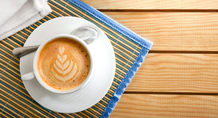 Coffee with flower drawing on wooden table top view