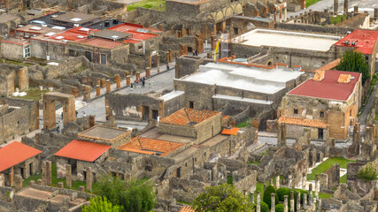 Fototapeta premium Aerial view of the ruins of houses and buildings of the ancient Roman city of Pompeii. The archaeological park is located in the province of Naples, Campania, Italy.