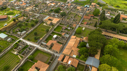 Obraz premium Aerial view of the ruins of houses and buildings of the ancient Roman city of Pompeii. The archaeological park is located in the province of Naples, Campania, Italy.