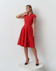 Elegant female model showcasing a stunning red dress in a chic studio setting