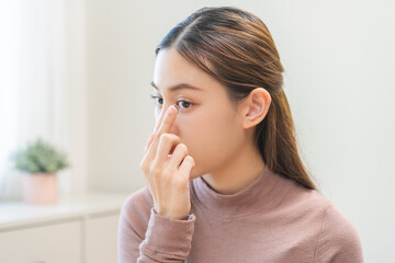 Ophthalmology care, eye sight, vision concept. Asian young woman, female hand holding and putting, wearing soft contact lenses with finger on face, girl looking in mirror at home, beauty and health.