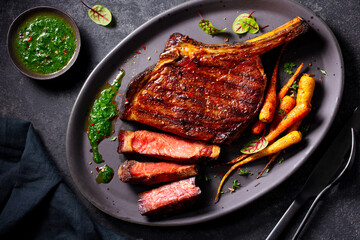 Grilled Tomahawk Steak and Carrots with Green Sauce. Close up. Top view.