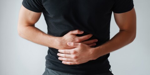 Man holds stomach in discomfort indicating possible health issue or digestive problem