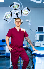 Confident surgeon in OR. A surgeon stands in an operating room, wearing scrubs and glasses, with...