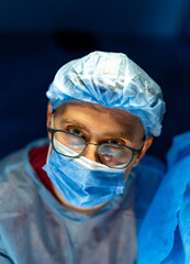 Surgeon readying for surgery. A medical professional wears scrubs and protective gear while...